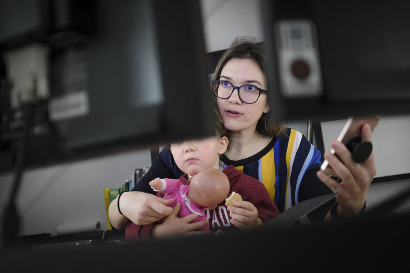 s:66:"Eine Mutter arbeitet mit ihrem minderjährigen Kind im Homeoffice.";