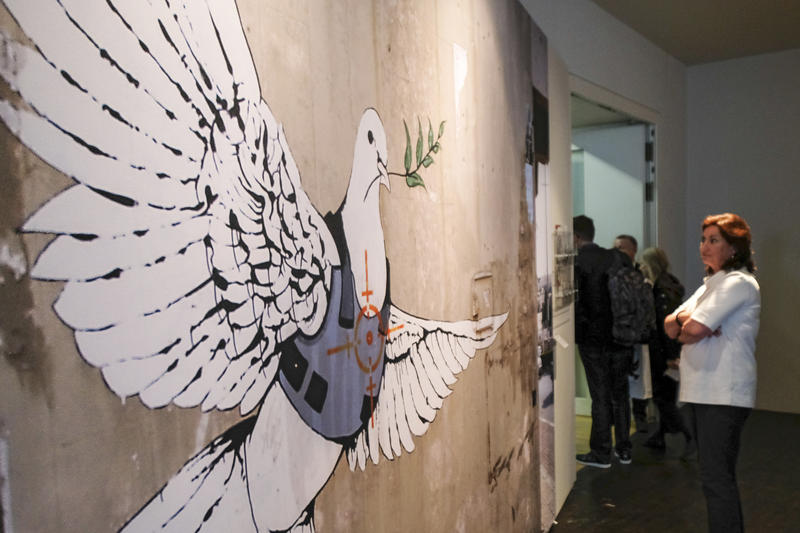 s:209:""Frieden. Von der Antike bis heute": Unter diesem Titel ruecken Museen in Muenster am 28.04.18 das Thema Frieden, seine Symbole und Rituale in den Blickpunkt. (Foto: "Taube in schusssicherer Weste" von Bangsy,";