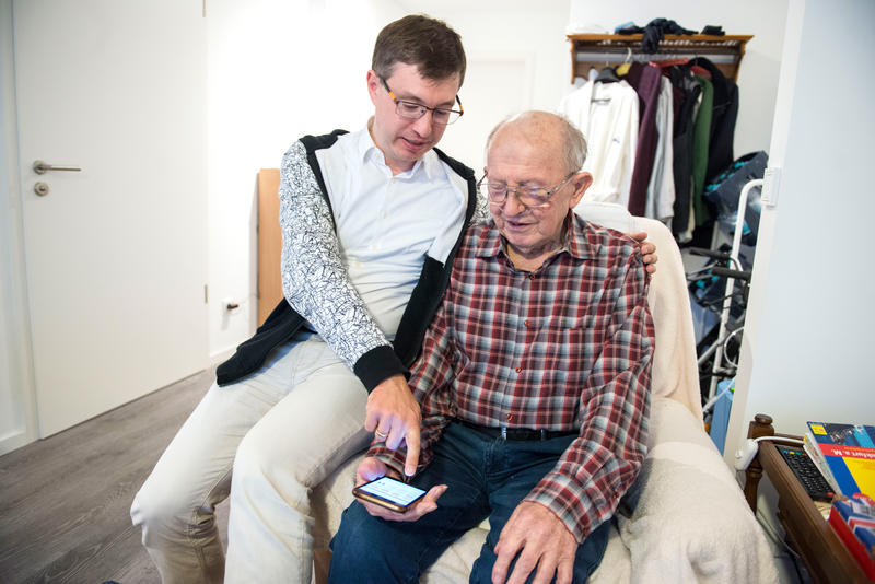 s:92:"Bruno Ehm (89) lässt sich von seinem Sohn Jörg den digitalen Sprachassistenten erklären. ";