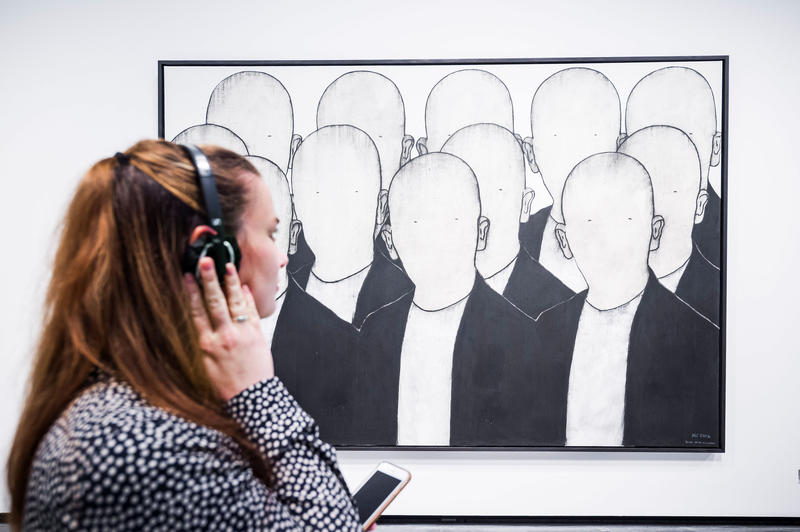 s:90:"Eine Besucherin der Ausstellung hört die für das Bild von Max Neumann komponierte Musik.";