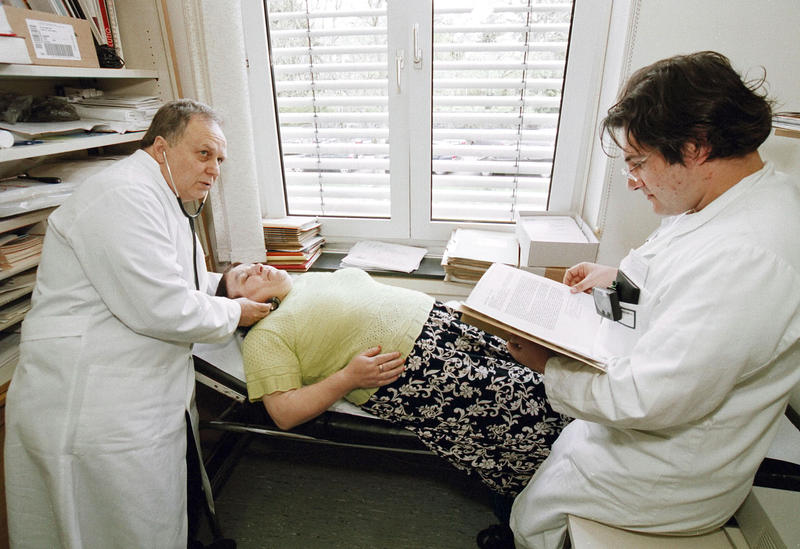 s:60:"Ärzte mit Migrationshintergrund untersuchen eine Patientin.";