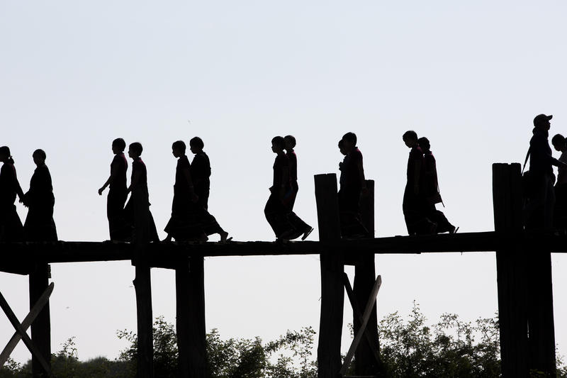 s:146:"Junge Novizinnen überqueren die U-Bein-Brücke am Taungthaman-See in Myanmar. Die Mehrheit der 53 Millionen Einwohner des Landes sind Buddhisten.";