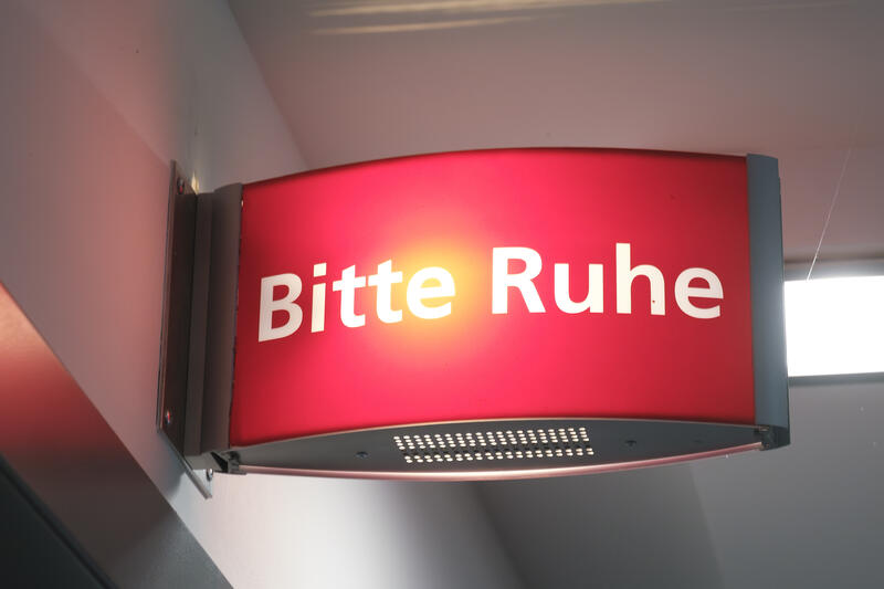 s:63:"Hinweisschild über der Tür eines Radiostudios bittet um Ruhe.";