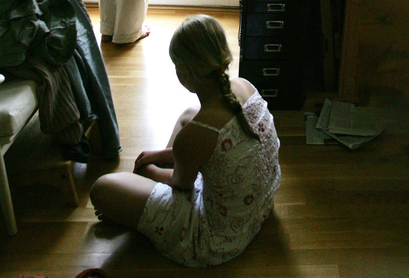 s:45:"Ein Mädchen sitzt schwermütig auf dem Boden";
