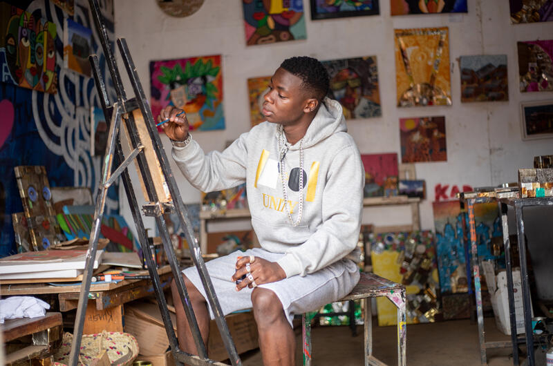 s:85:"Saviour Juma arbeitet im "Art Sun Valley Collective" in Kibera an einem seiner Werke.";