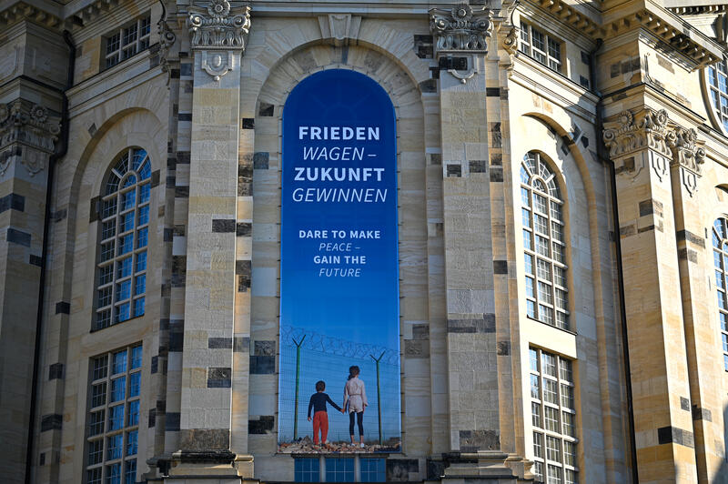 s:89:"Banner an der Dresdner Frauenkirche mit der Aufschrift "Frieden Wagen - Zukunft Gewinnen"";