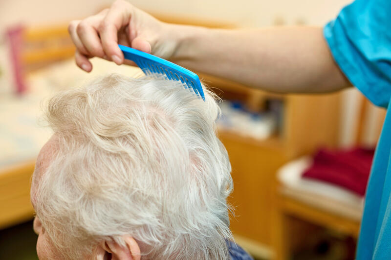 s:63:"Pflegekraft kämmt einer Bewohnerin eines Pflegeheims die Haare";