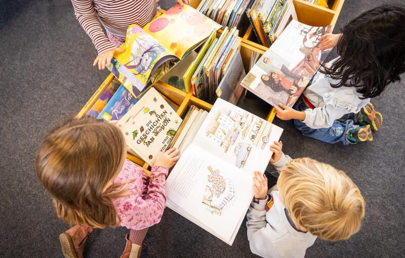s:121:"Kinder einer Vorschulklasse stöbern in den Bücherkisten der Kinder- und Jugendbibliothek der Stadtbibliothek Osnabrück";