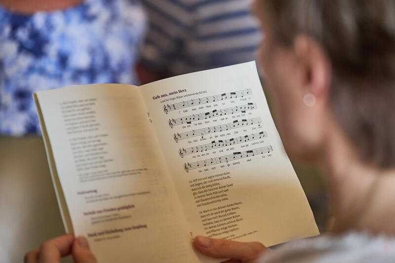 s:30:"Eine Frau hält ein Liederbuch";