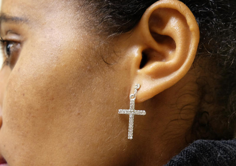 s:41:"Christin trägt ein Kreuz als Ohrschmuck.";