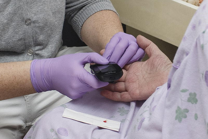 s:92:"Eine Mitarbeiterin eines ambulanten Pflegedienstes misst einer Patientin den Blutzuckerwert.";