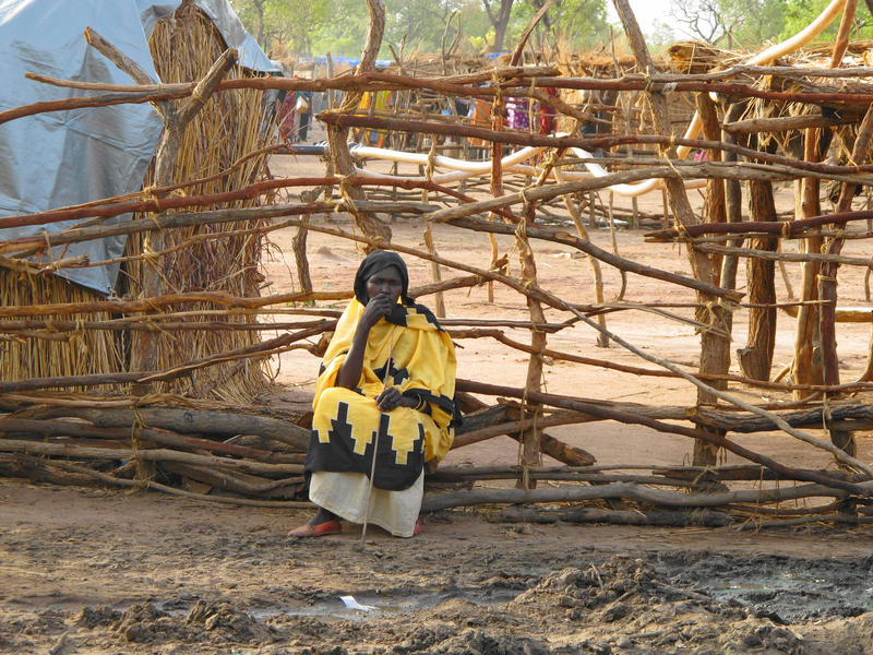 s:73:"Eine Frau sitzt erschöpft am Wegesrand im Flüchtlingslager im Südsudan";
