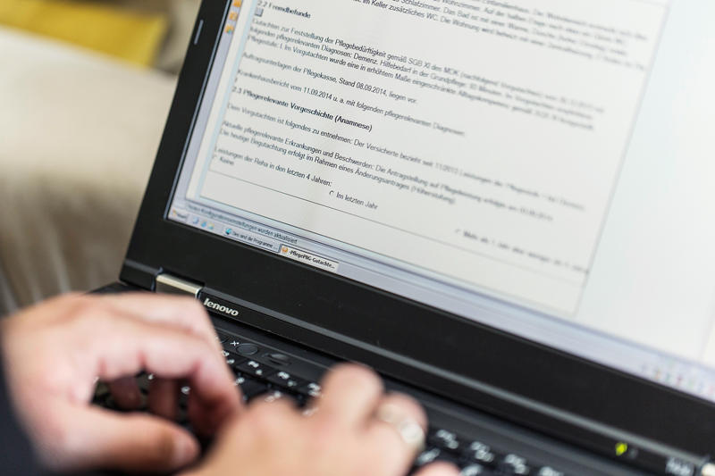 s:125:"Ein Mitarbeiter des Medizinischen Dienstes der Krankenkassen schreibt seine Beurteilung für einen Pflegegrad einer Seniorin.";