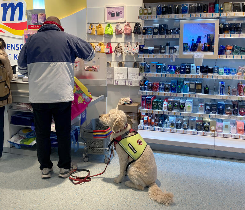 s:69:"Detlef Sander mit Assistenzhund Kira in einem Drogeriemarkt in Berlin";