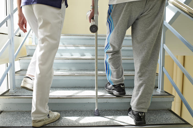 s:71:"Eine Physiotherapeutin bei Gehübungen mit einem Patienten (Themenfoto)";