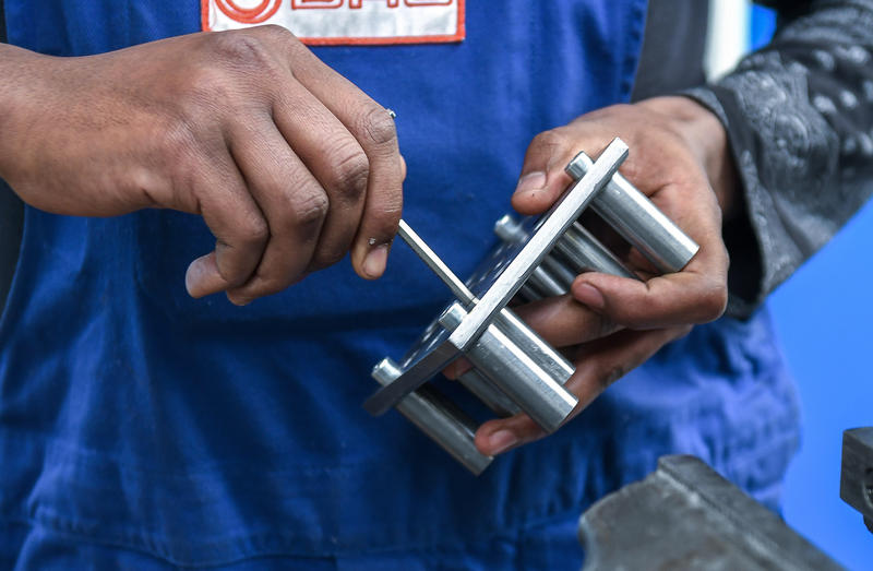 s:45:"Migrant an einer Werkbank in einem Stahlwerk.";