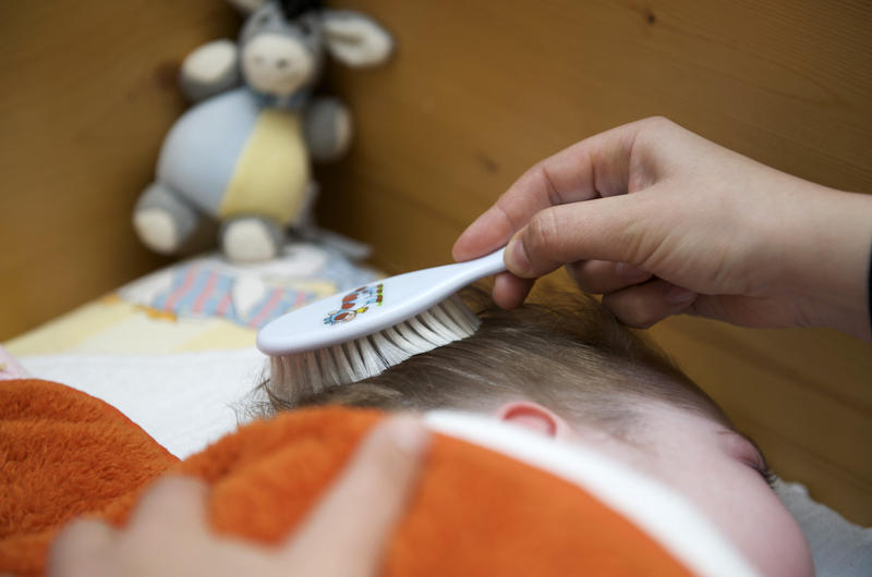 s:40:"Ein Mutter kämmt das Haar ihres Kindes.";