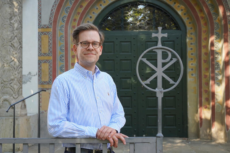 s:59:"Pfarrer Andreas Braveny vor der Erlöserkirche in München.";