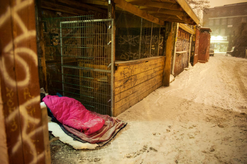 s:61:"Ein Obdachloser liegt im Winter draußen in einem Schlafsack.";